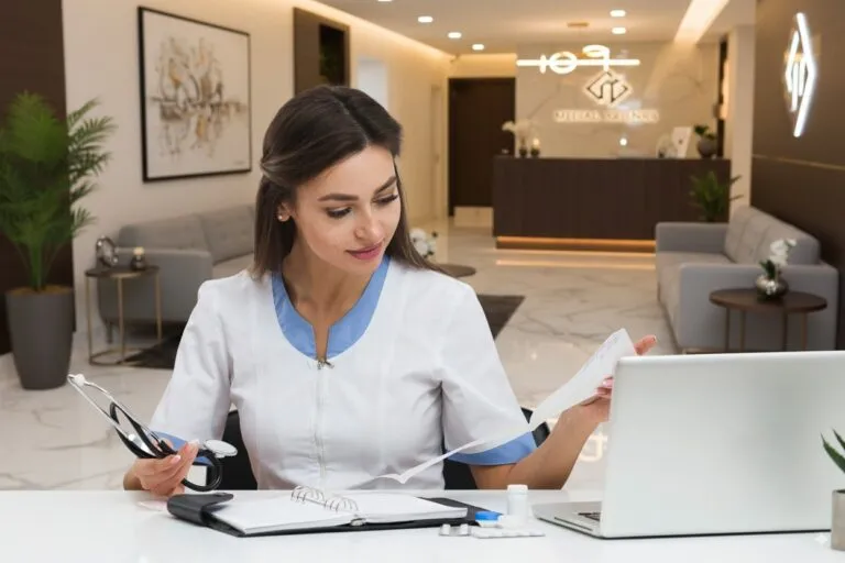 Recepcionista de clínica confirma e reagenda consultas no notebook com IA via WhatsApp, reduzindo no-show na recepção de um consultório moderno.