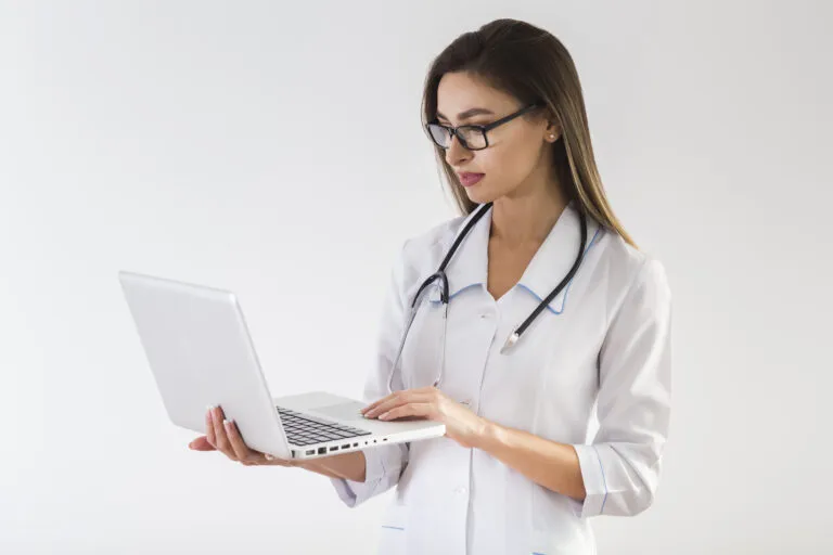Médica com estetoscópio usando notebook para acessar software médico em nuvem — agenda, prontuário eletrônico e comunicação via WhatsApp.