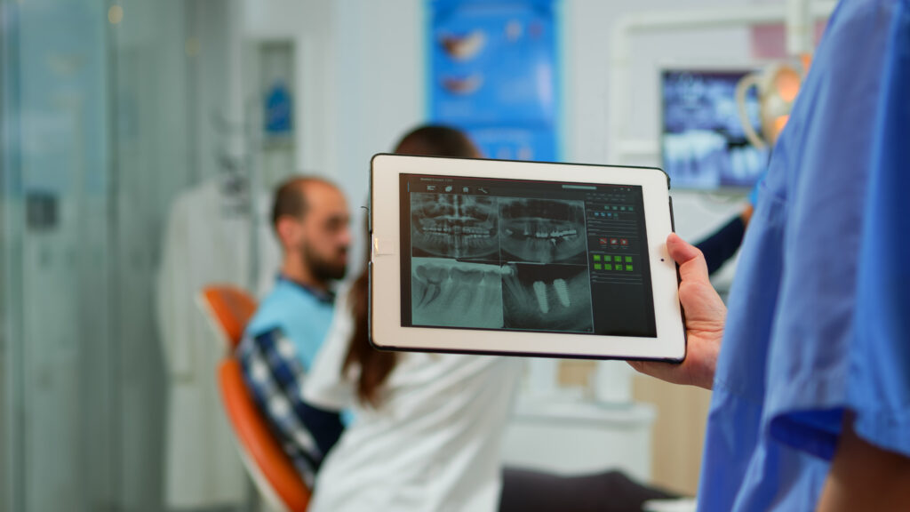 Tablet mostrando software de IA classificando pacientes por potencial de compra em clínica odontológica.