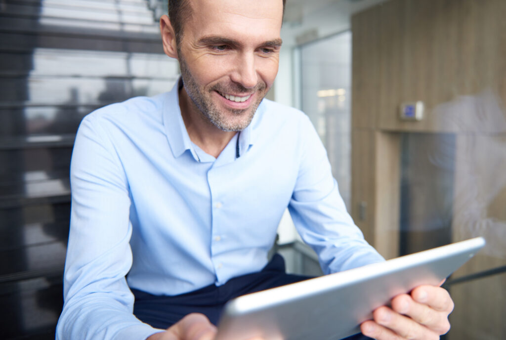 Dentista gestor analisando gráfico de redução de no-show e aumento de lucro no tablet.